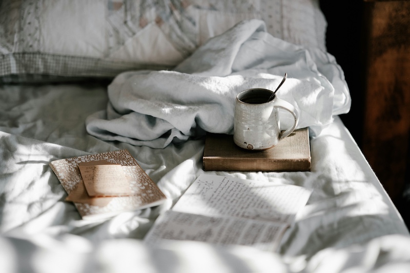 white bed with a mug and books
